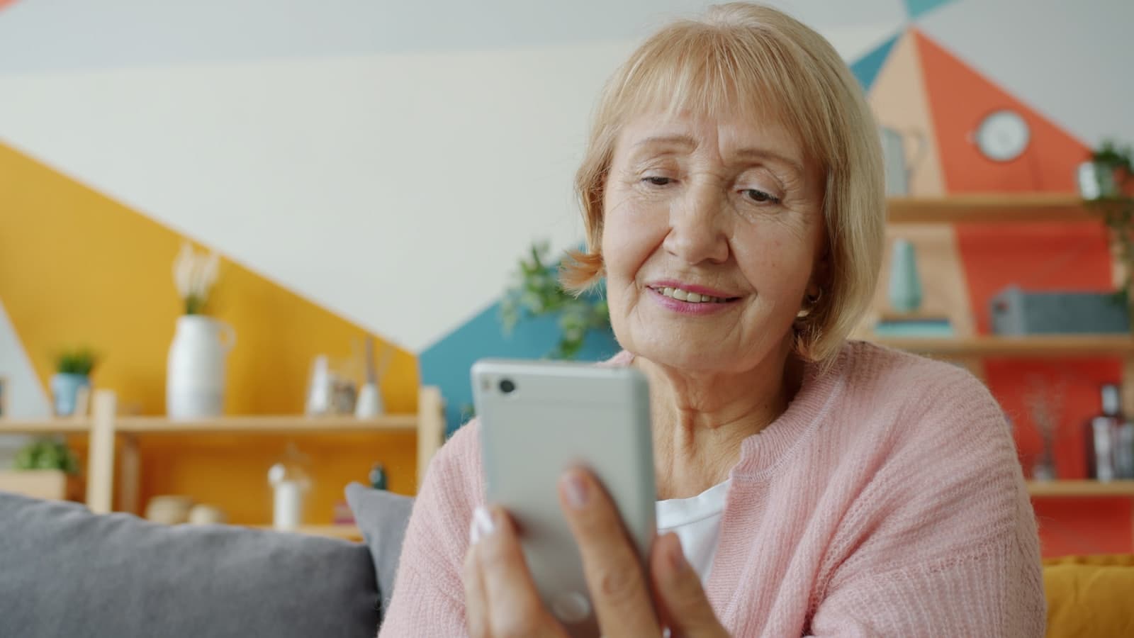 A smiling older woman reading a check-in text on her phone